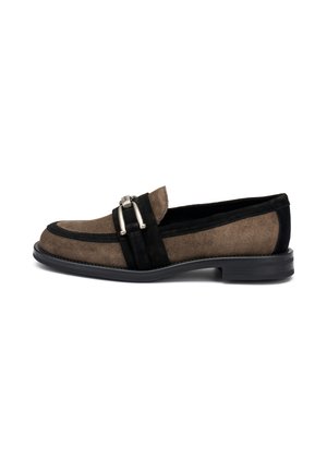 Mocasines de ante en marrón y negro con una textura suave, que presentan una prominente hebilla plateada y un bajo tacón de goma negra.