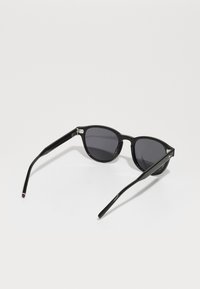 Ochelari de soare negri cu lentile întunecate, design cu ramă rotundă, finisaj lucios și brațe subțiri. Hardware argintiu notabil la balamale.
