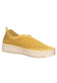 Scarpa gialla a slip-on perforata con tomaia testurizzata, forma arrotondata e suola spessa bianca con scanalature verticali.