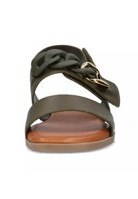 Sandalo verde oliva con un cinturino intrecciato, un accento in metallo dorato e una suola in legno liscia. Fibbia in pelle regolabile sul lato.