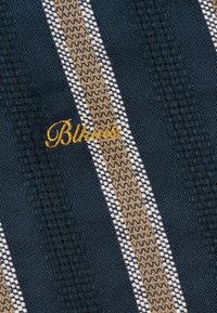 Tissu texturé bleu foncé avec des rayures verticales beiges et blanches et une broderie cursive jaune "Bikkurio".