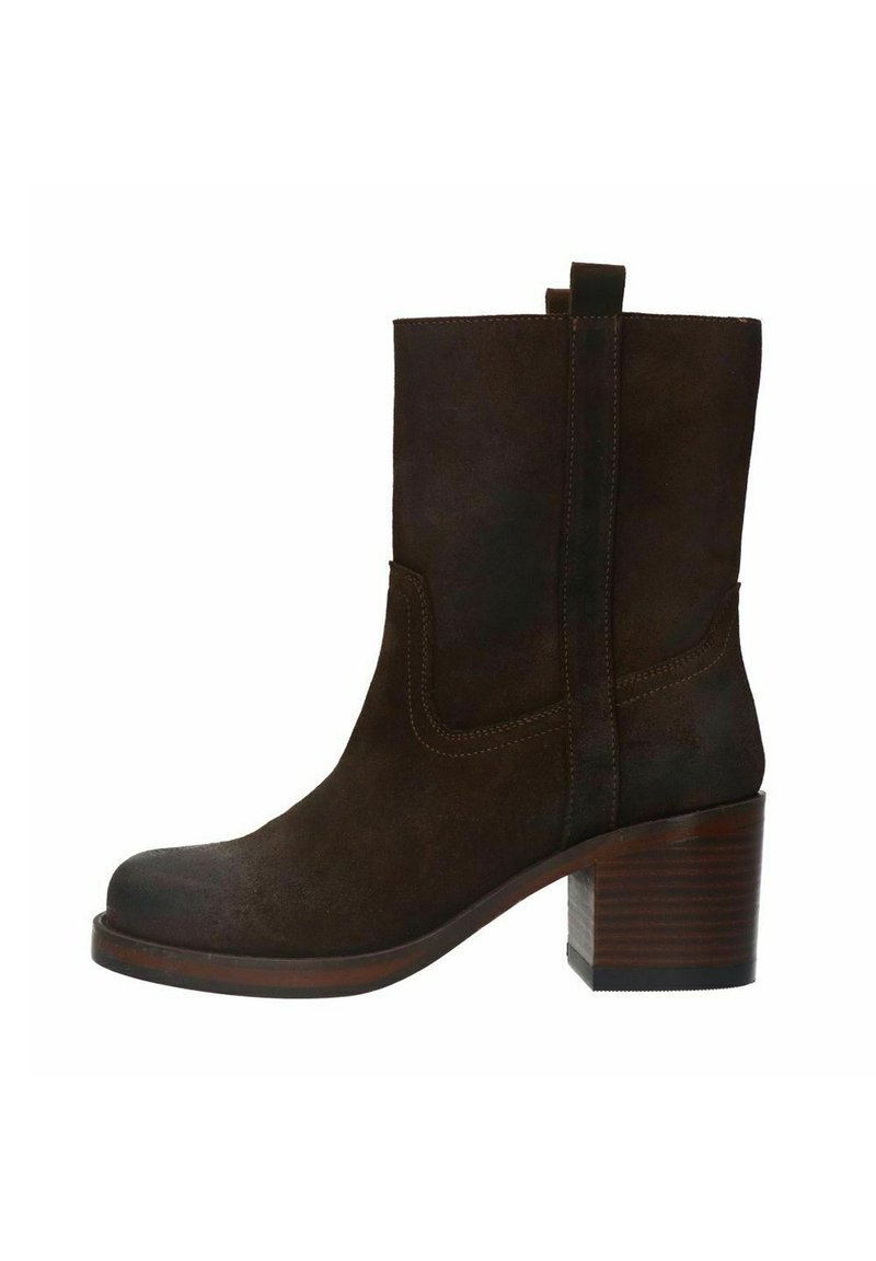 Bottine en suede marron avec un bout carré et un talon empilé de 5 cm. Présente des accents cousus et une languette à l'arrière pour un enfilage facile.