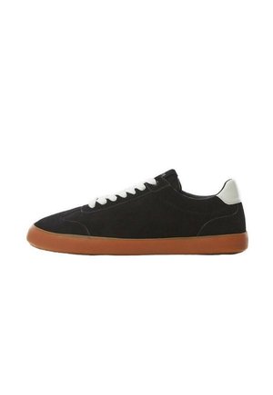 Czarny zamszowy niskoprofilowy sneaker z białymi sznurowadłami, białą taśmą na pięcie i gumową podeszwą, pokazany z profilu na białym tle.