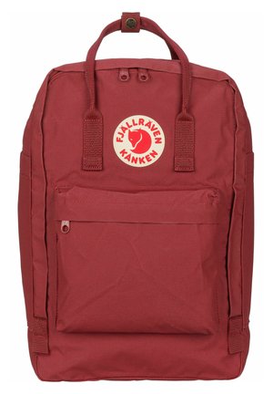 Sac à dos Fjällräven Kanken rouge en tissu durable. Il comprend des poignées doubles sur le dessus, une poche zippée à l'avant et un logo circulaire à l'avant.