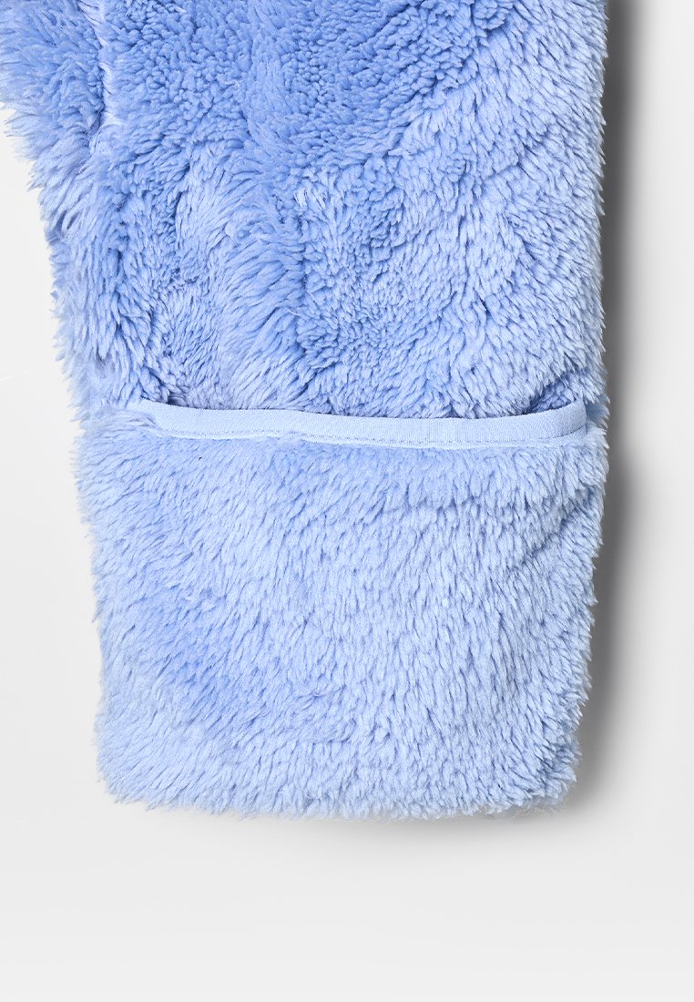 Tejido de forro polar esponjoso de color azul claro con una textura suave, que presenta un bolsillo cosido a lo largo del borde inferior.