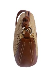 Bolso de hombro trenzado en tono marrón claro con acentos de cuero marrón, de forma redondeada y con herrajes metálicos y una correa de cuero. Se aprecia un detalle de superficie texturizada.