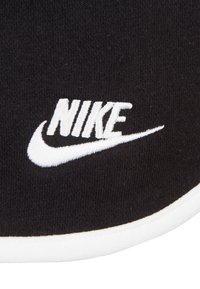 Svart tyg med vit "NIKE"-logotyp och swoosh-broderi. Slät textur med en kontrasterande vit kant längs kanten.