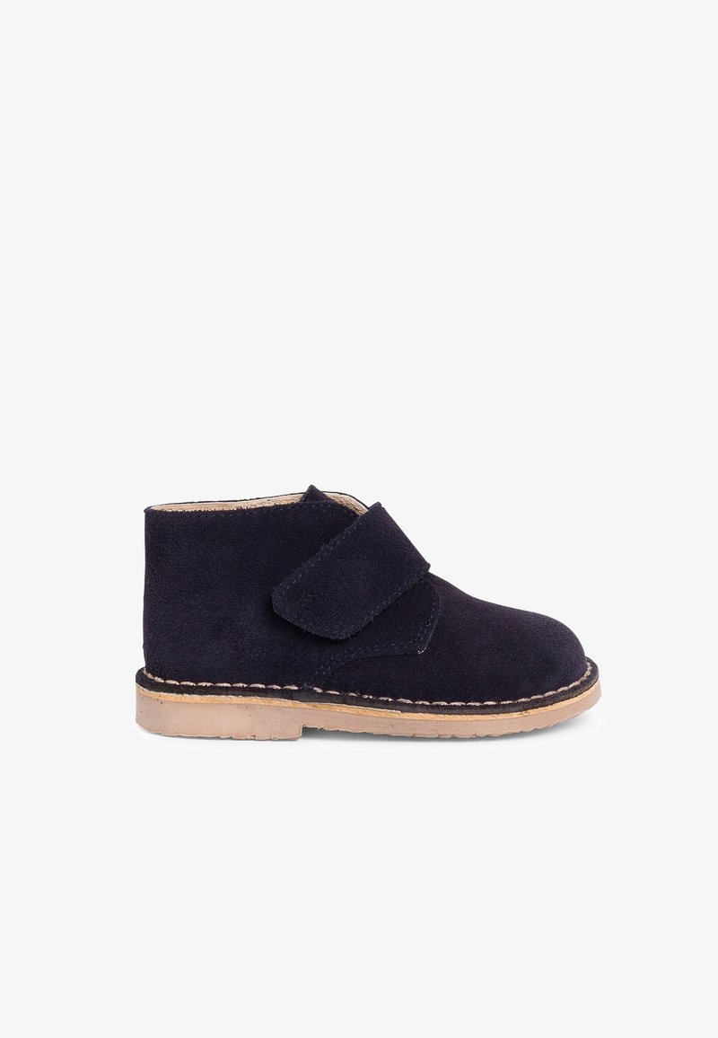 Bottine enfant en daim bleu foncé avec semelle beige et large fermeture velcro sur fond blanc.