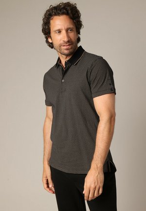 T-shirt polo noir à manches courtes avec un motif géométrique, un col contrasté et une patte de boutonnage à deux boutons. Tissu doux et respirant.
