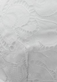 Witte kantstoffen met ingewikkelde bloemmotieven en texturen, die verschillende weefsels en een zachte, luchtige feel benadrukken.