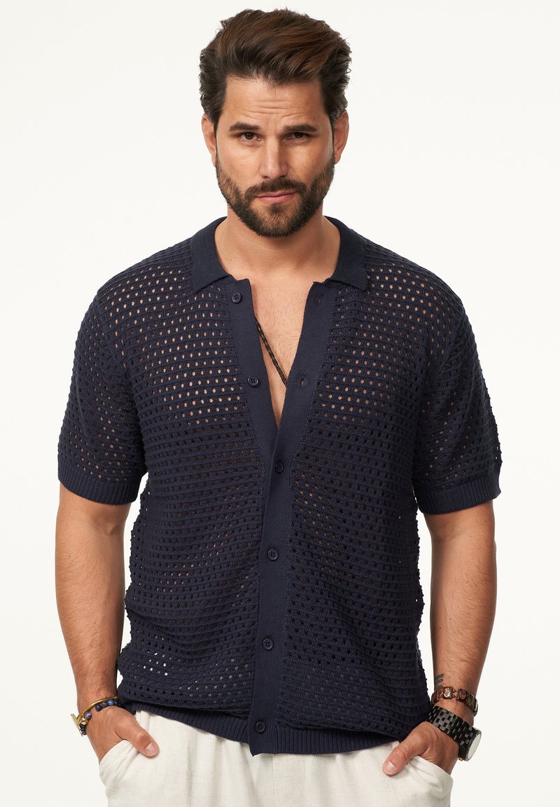 Navyblaues Kurzarm-Strickshirt mit strukturiertem, offener Webart, Knopfleiste und klassischem Kragen. Mit gerippten Bündchen und Saum.