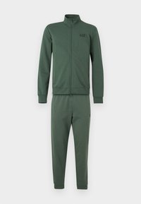 Φόρμα από σκούρο πράσινο ύφασμα, με ζακέτα με φερμουάρ και γιακά, καθώς και αντίστοιχο παντελόνι με στενή γραμμή. Περιλαμβάνει μικρή λεπτομέρεια λογότυπου στη ζακέτα.