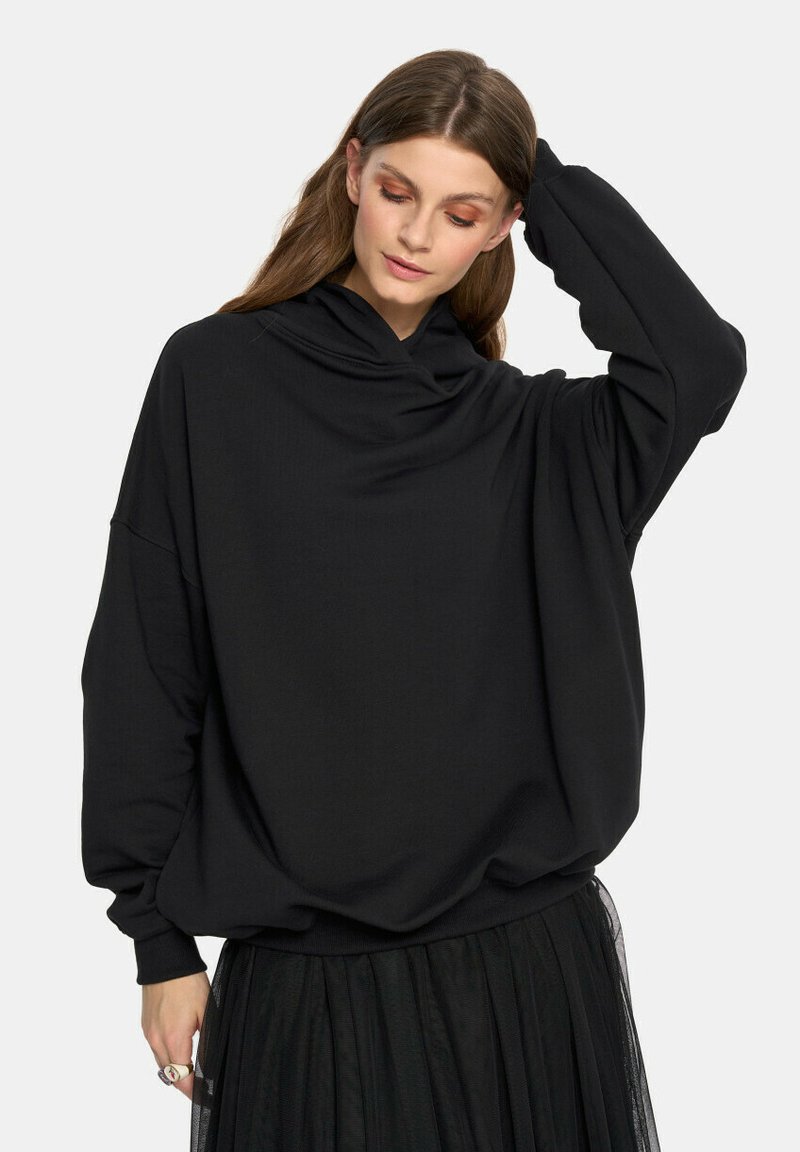 Czarny, oversize bluza z długim rękawem i luźnym dekoltem, wykonana z miękkiej bawełny. Połączona z warstwową spódnicą z czarnego tiulu.