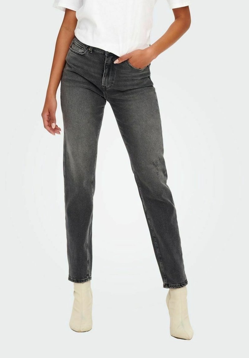 Jean noir taille haute avec une coupe droite, une finition délavée et un design à cinq poches, associés à des bottines légères.