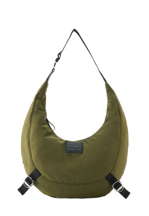 Olivgrüne, sichelförmige Schultertasche mit schwarzen verstellbaren Trägern und "Studio Berlin" Aufnäher auf der Vorderseite.
