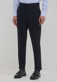 Marineblaue, taillierte Hosen mit schmaler Passform, aus glattem Stoff gefertigt, mit flachem Frontteil, seitlichen Taschen und einem dezenten Knopfverschluss.
