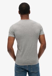 Grå kortærmet t-shirt med rund halsudskæring, lavet af blødt stof. Har en tætsiddende silhuet og sømløs skulderdesign.