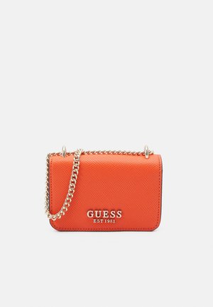 Bolso bandolera naranja texturizado con correa de cadena dorada y logo "GUESS EST 1981" en el frente sobre fondo blanco liso.