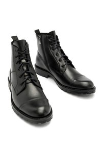 Czarne skórzane botki za kostkę z sznurowanym przodem, okrągłym noskiem i teksturowaną gumową podeszwą. Posiadają zamek błyskawiczny z boku dla łatwego zakładania.