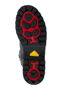 Schwarze Gummisohle eines Stiefels mit markantem Profilmuster. Rote und gelbe Bauteile aus Metall für ein Skibindungssystem.