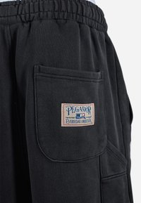 Sorte sweatpants med elastisk talje og en stor sidelomme med en multicolor "PAGADOR EVERYDAY AMBITION" label på.