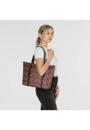 Sac tote en tissu texturé avec un motif en chevrons, comprenant des nuances de brun, rouge et bleu, avec des anses en cuir brun et un design spacieux.