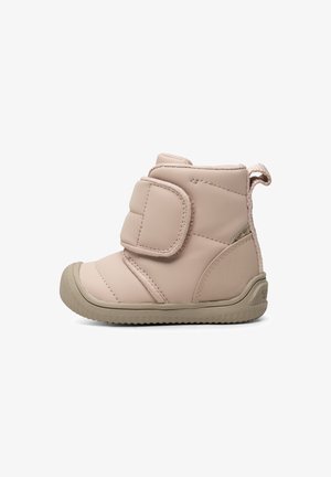 Bota aislante de color rosa pálido con punta redondeada, superficie texturizada, una correa de Velcro y una suela de goma resistente y acanalada. Diseño general compacto.