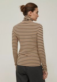 Maglione beige aderente a collo alto con strisce orizzontali nere, maniche lunghe, texture morbida e colletto alto, mostrato di spalle.