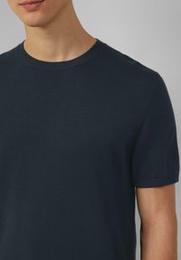 Navyblauwe gebreide t-shirt met een ronde halslijn en korte mouwen. Zachte textuur en geribbelde accenten bij de kraag en mouwen.