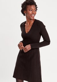 Braun geripptes Strickkleid mit V-Ausschnitt, langen Ärmeln und einem schwingenden Rock mit vertikalen Schlitz. Glatte Textur und figurnahes Design.