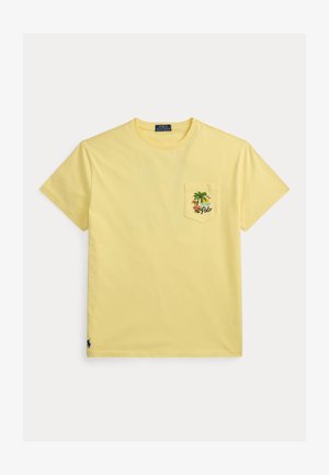 Żółta krótka koszulka z okrągłym dekoltem i kieszonką na piersi z tropikalnym wzorem przedstawiającym palmę, słońce, kwiaty oraz napis "Polo".