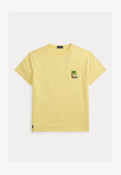 Κίτρινο κοντομάνικο t-shirt με στρογγυλή λαιμόκοψη και τσέπη στο στήθος που διαθέτει τροπικό σχέδιο με φοινικόδεντρο, ήλιο, λουλούδια και τη λέξη "Polo".