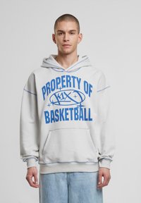 Világosszürke kapucnis pulóver kék felirattal: "A BASKETBALL TULAJDONA", kenguru zsebbel és húzott ujjal. Puha anyag, laza szabás.