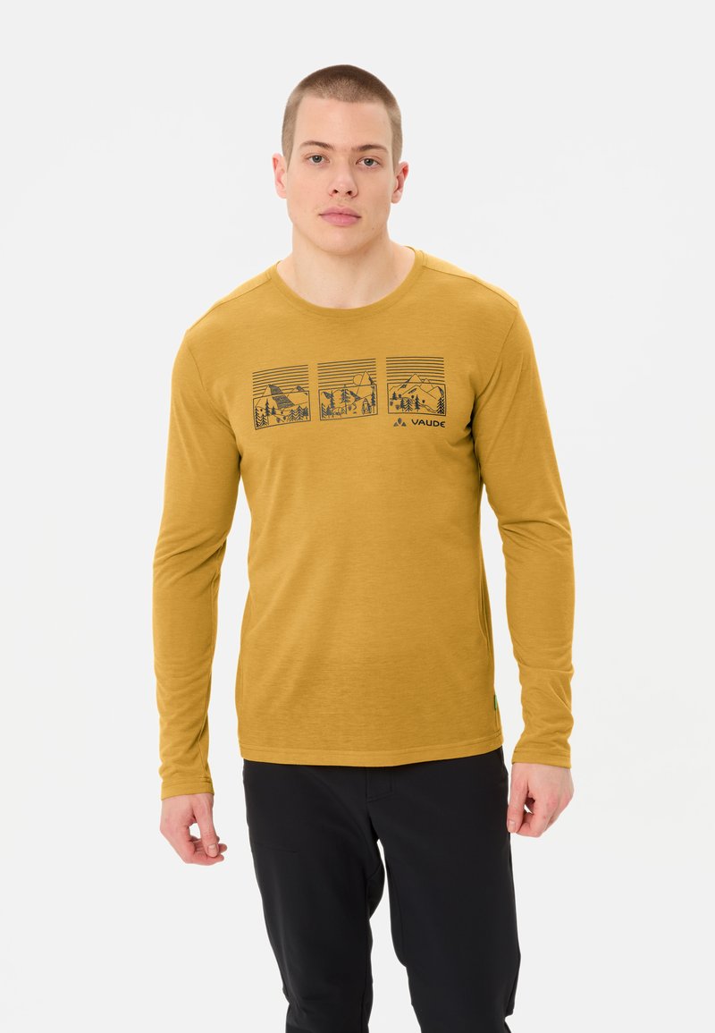 Chemise à manches longues jaune moutarde avec un col rond. Présente trois motifs de paysages de montagnes en impression noire sur la poitrine.