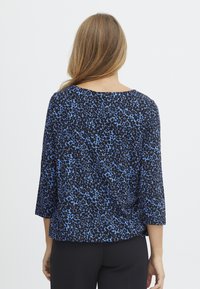 Blusa leopardata nera e blu con maniche a tre quarti, colletto tondo e vestibilità comoda, realizzata in un tessuto leggero e liscio.