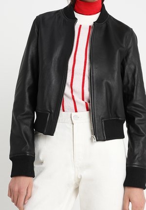 Zwarte leren bomberjack met ribgebreide manchetten, ritsluiting en een eenvoudige stijl, gedragen over een rood-wit gestreepte trui.