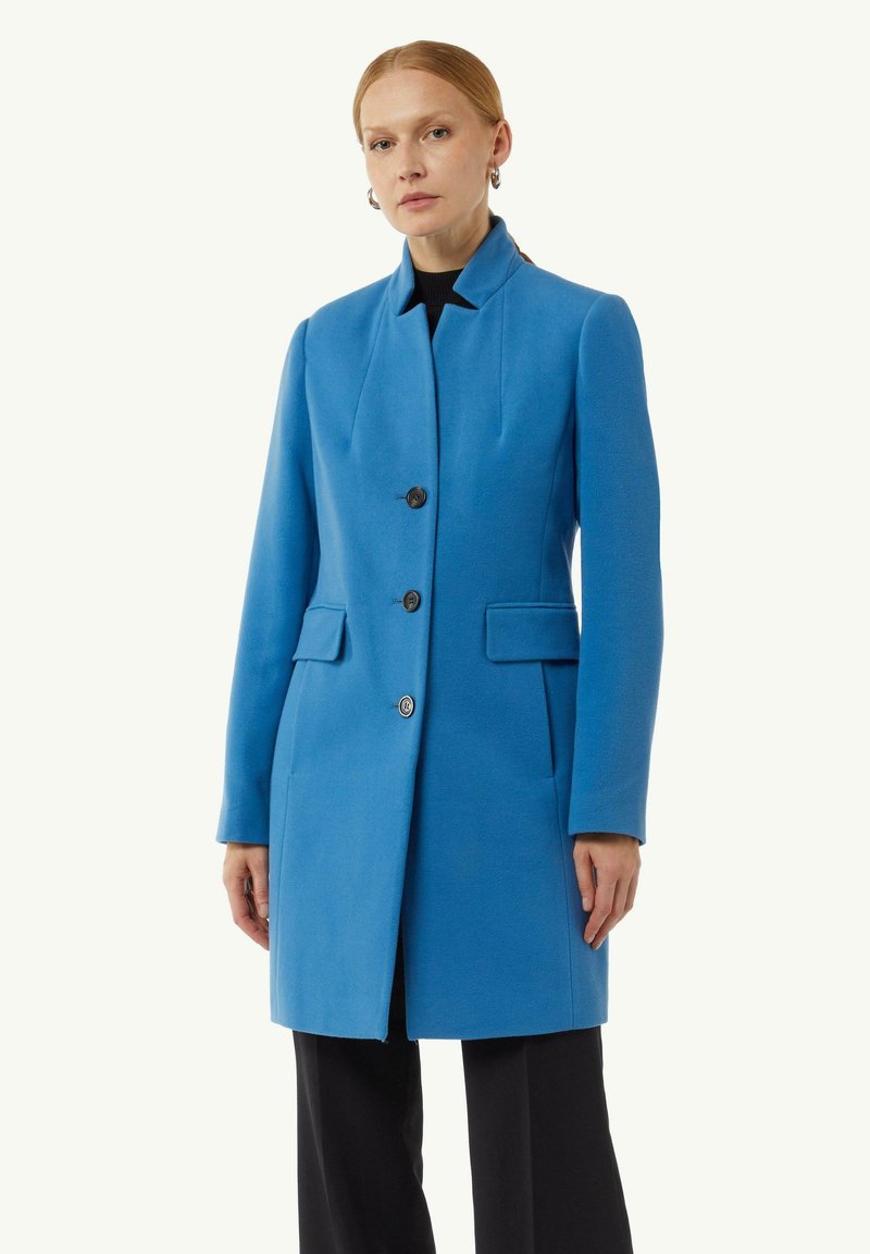 Blauer Wollmantel mit taillierter Passform, Reverskragen, drei Knöpfen und Seitentaschen. Der Stoff hat eine glatte Textur und eine strukturierte Form.
