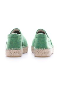 Zapatillas verdes de fieltro sin cordones con suela de yute trenzada. Parte trasera redondeada con hardware mínimo, que presenta una superficie texturizada y un diseño informal.