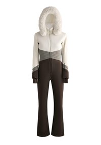 Síkombiné fehér, texturált varrással díszített felsőrésszel, világosszürke és sötétbarna részekkel, szőrmebéléses kapucnival és bővülő barna nadrágszárakkal.