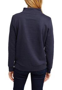 Marinblå sweatshirt med hög krage, ribbad mudd och nederkant. Designad i ett mjukt tyg med en slät textur och synliga sömnadsdetaljer.