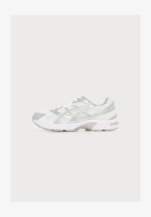 Baskets de sport blanches et grises avec tige en mesh, fermeture à lacets et semelle rembourrée, vues de profil sur un fond clair uni.