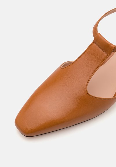 Pruun nahkne slingback king, millel on terav nina, avatud küljed ja tekstureeritud viimistlus. Omab kitsast pahkluu rihma, et tagada kindel sobivus.
