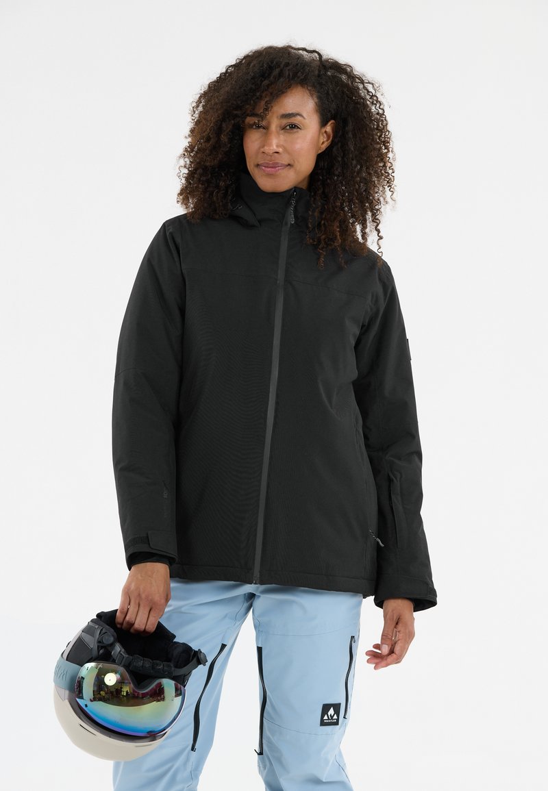 Schwarze, wasserdichte Jacke mit hohem Kragen, Reißverschluss vorne und strukturiertem Finish, kombiniert mit hellblauen Schneehosen und einem Helm mit verspiegeltlichem Visier.
