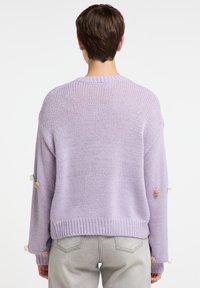Lavendelfarbener gestrickter Pullover mit lockerer Passform, mit geripptem Saum und drei Pompons an jedem Ärmel in hellen Farben. Dezente Textur im gesamten Pullover.