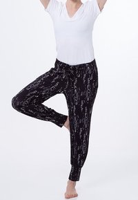 Svarta mönstrade joggerbyxor med en flödande design, elastiska muddar och dragsnören i midjan, kombinerade med en vit t-shirt med kort ärm.