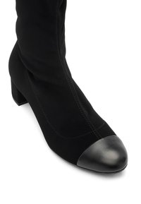 Bottines noires mi-mollet avec un talon carré et un bout arrondi lisse, présentant des détails de couture visibles sur l'avant et les côtés.