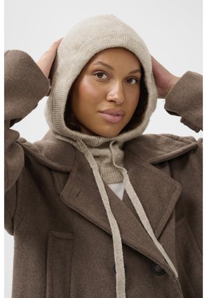 Brown wool peacoat with large lapels and front pockets, layered over a beige hoodie with a ribbed hem and contrasting drawstrings.