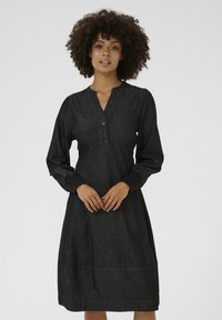 Zwarte denim jurk met lange, opgeblazen mouwen, V-hals, knoopdetail en een ruime pasvorm, met een licht uitlopende rok en zichtbare stiksels.
