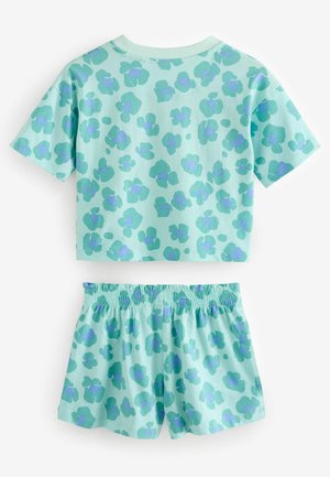 Ljusblå tvådelad dräkt med en kortärmad topp och shorts med elastisk midja, båda med ett mönster av mörkblå abstrakta former.