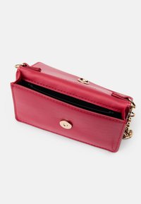 Lyserød læderpunge med en guldknaplukning og kædesnor. Har en lynlåslomme og en glat overflade. Kompakt rektangulær form.